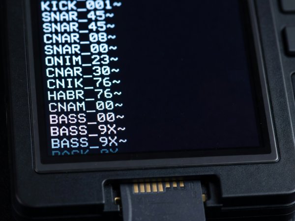 Close-up of a hardware sampler OLED screen showing truncated 12-character filenames where front-loaded instrument codes remain readable